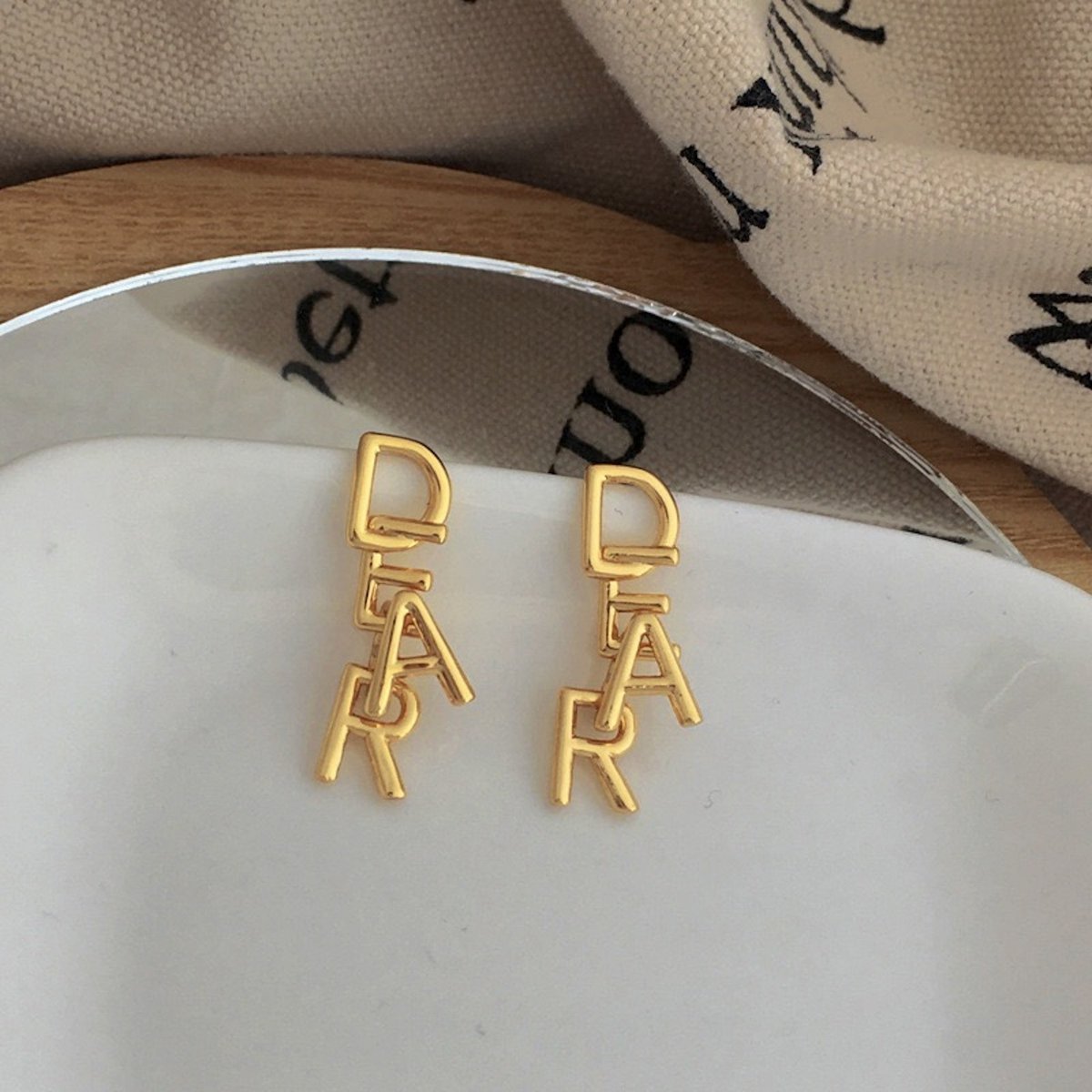 Letras DEAR entrelazadas: románticos pendientes dorados con una esencia lúdica y minimalista