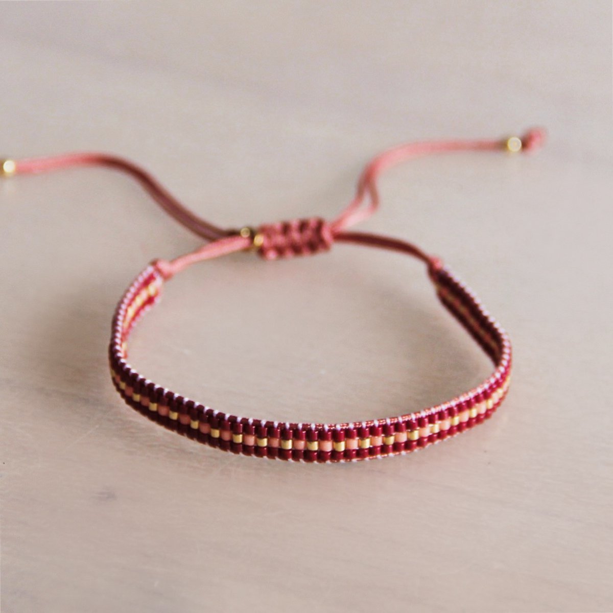 Gevlochten armband bordeaux/perzik/verguld